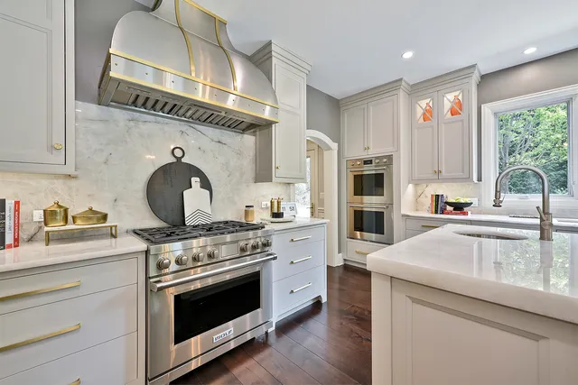 a large kitchen with kitchen island a large counter top a sink a window and stainless steel appliances