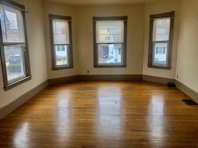 a view of an empty room with wooden floor and windows