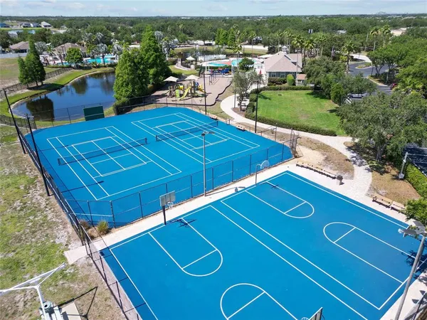 a view of a tennis ground with large trees