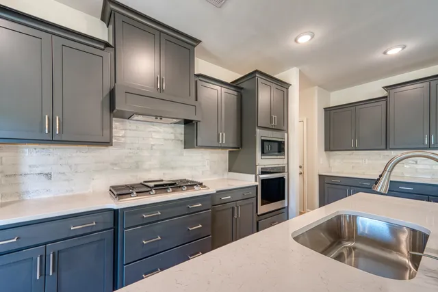 a large kitchen with stainless steel appliances granite countertop a sink a stove and a refrigerator