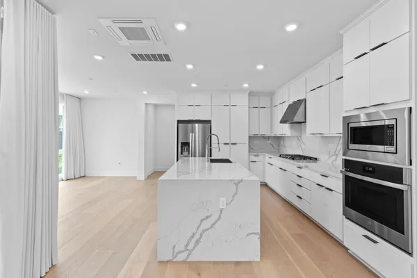 a large kitchen with stainless steel appliances kitchen island a stove a sink a refrigerator and a microwave