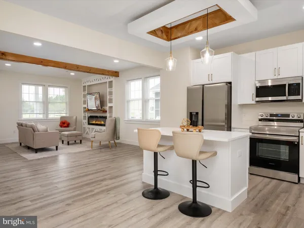 a kitchen with stainless steel appliances kitchen island granite countertop a stove a refrigerator and a dining table with wooden floor