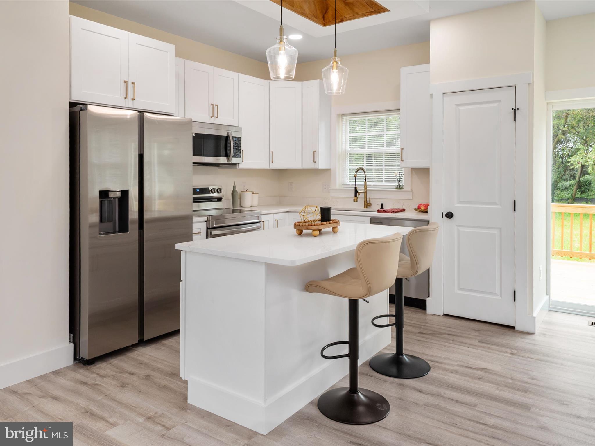 1 Sunrise Avenue Ridgely, MD 21660 - Photo 9 of 28 a kitchen with stainless steel appliances a refrigerator a sink a stove and white cabinets with wooden floor