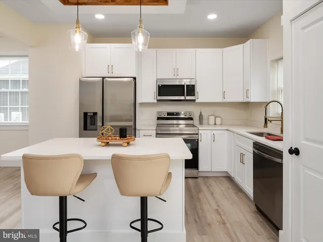 a kitchen with stainless steel appliances a table chairs refrigerator and microwave