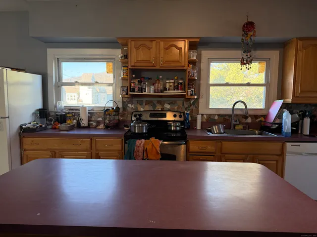 a kitchen with kitchen island granite countertop a sink cabinets and a large window