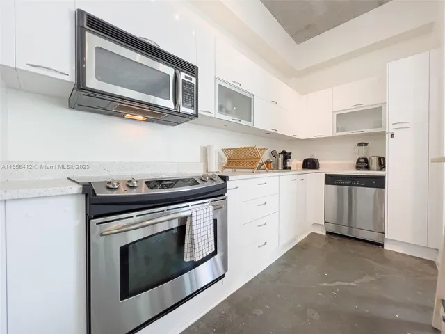 a kitchen with cabinets stainless steel appliances and wooden floor