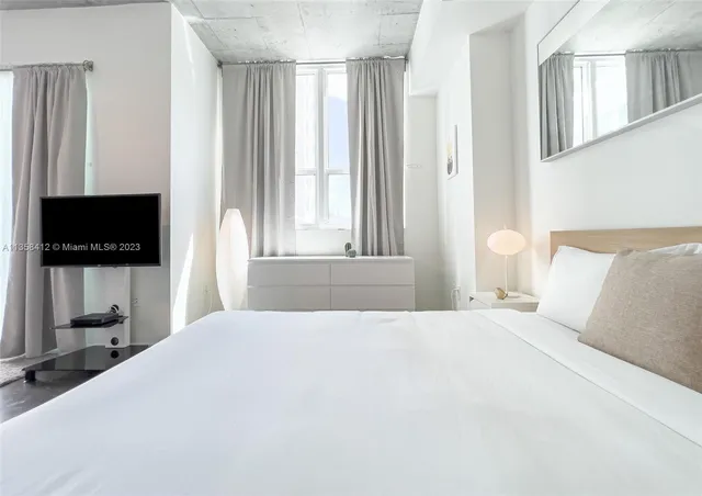 a bedroom with a large bed and a flat screen tv