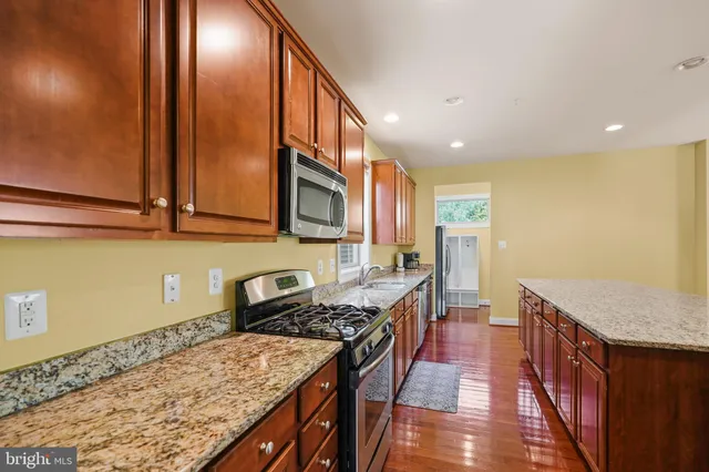 a kitchen with stainless steel appliances granite countertop a sink a stove and a wooden floors