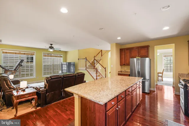 a kitchen with granite countertop a stove a sink a refrigerator and cabinets