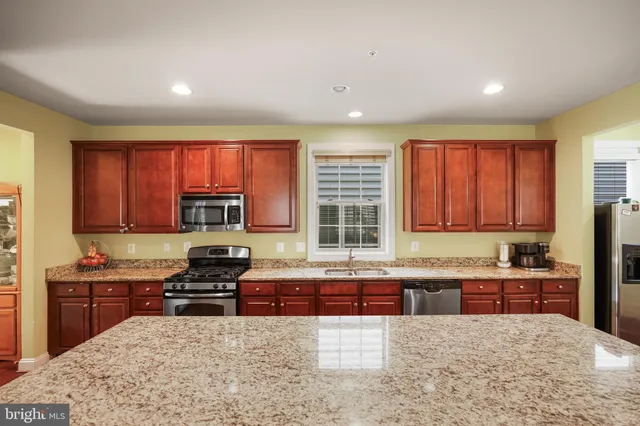 a kitchen with stainless steel appliances granite countertop wooden cabinets a stove top oven a sink and dishwasher