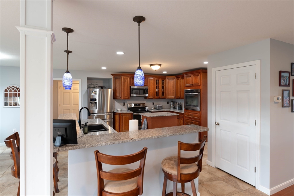 83 Bay Road Hadley, MA 01035 - Photo 6 of 36 a kitchen with kitchen island a stove a refrigerator a dining table and chairs with wooden floor