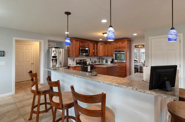a kitchen with stainless steel appliances granite countertop dining table chairs and a refrigerator