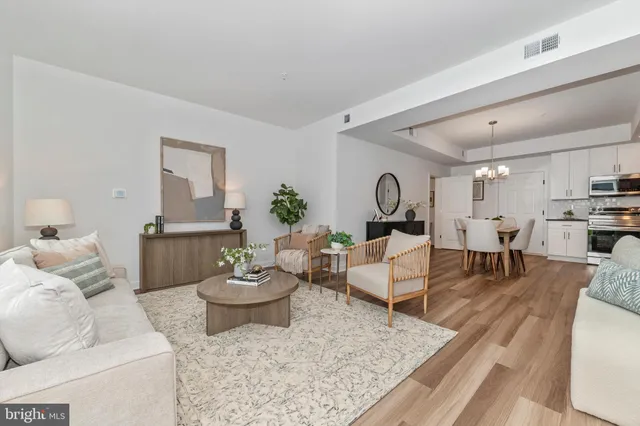 a living room with furniture and a dining table with wooden floor
