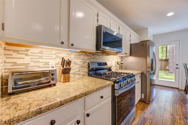 a kitchen with granite countertop a stove and a wooden floor