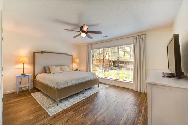 a bedroom with a large bed and a flat tv screen on dresser
