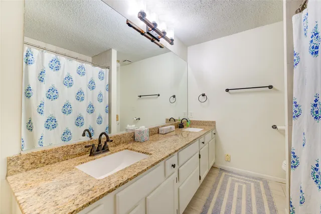 a bathroom with a granite countertop sink mirror and a shower