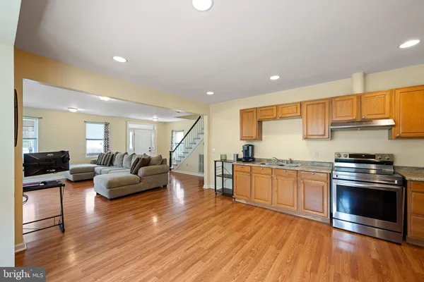 a kitchen with granite countertop a stove top oven a sink dishwasher a dining table and chairs with wooden floor