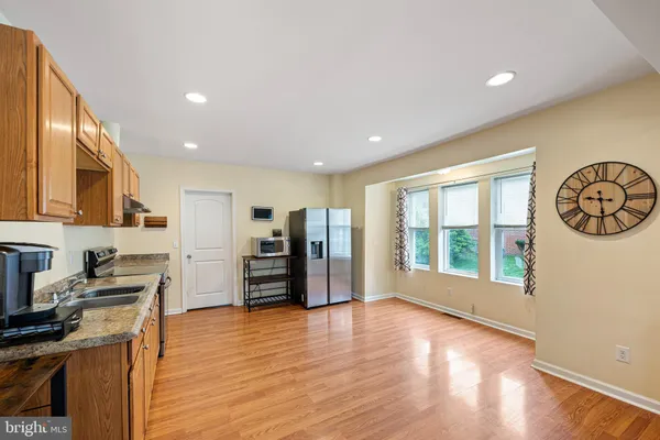 a view of a kitchen with a stove top oven a refrigerator a kitchen island with wooden floor and cabinets