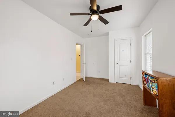 an empty room with ceiling fan and window