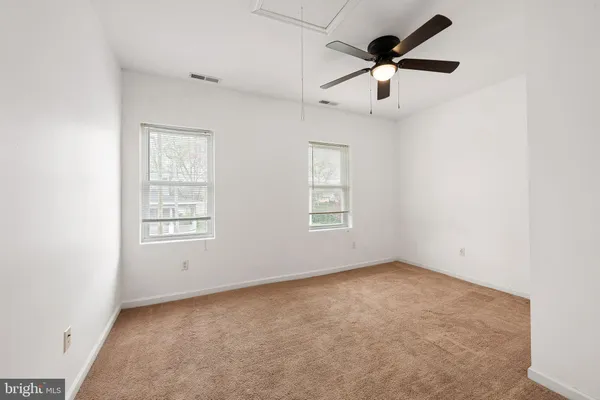 an empty room with ceiling fan and windows