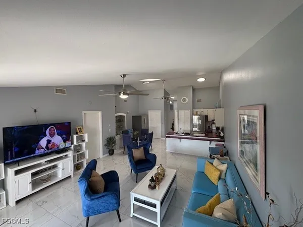 a living room with furniture a flat screen tv and kitchen view