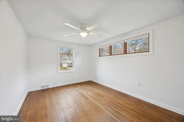 a view of an empty room with window and wooden floor