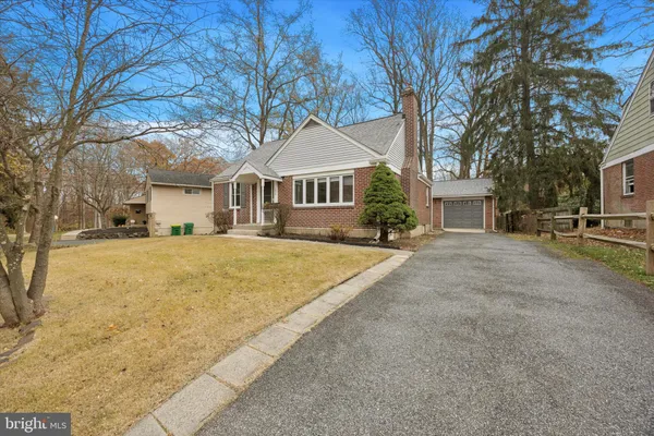 a front view of a house with large trees