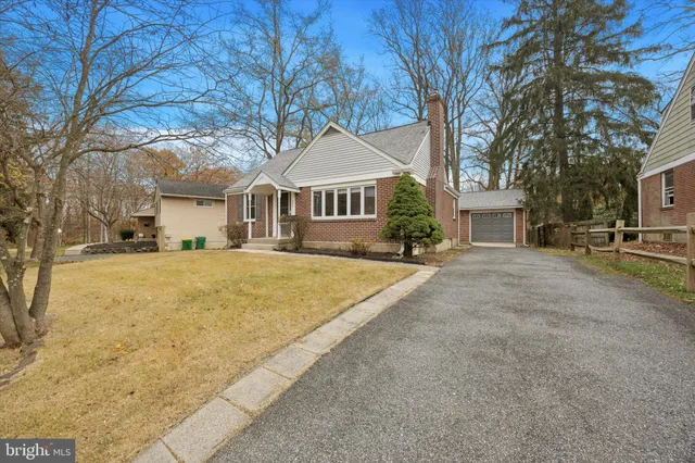 a front view of a house with large trees