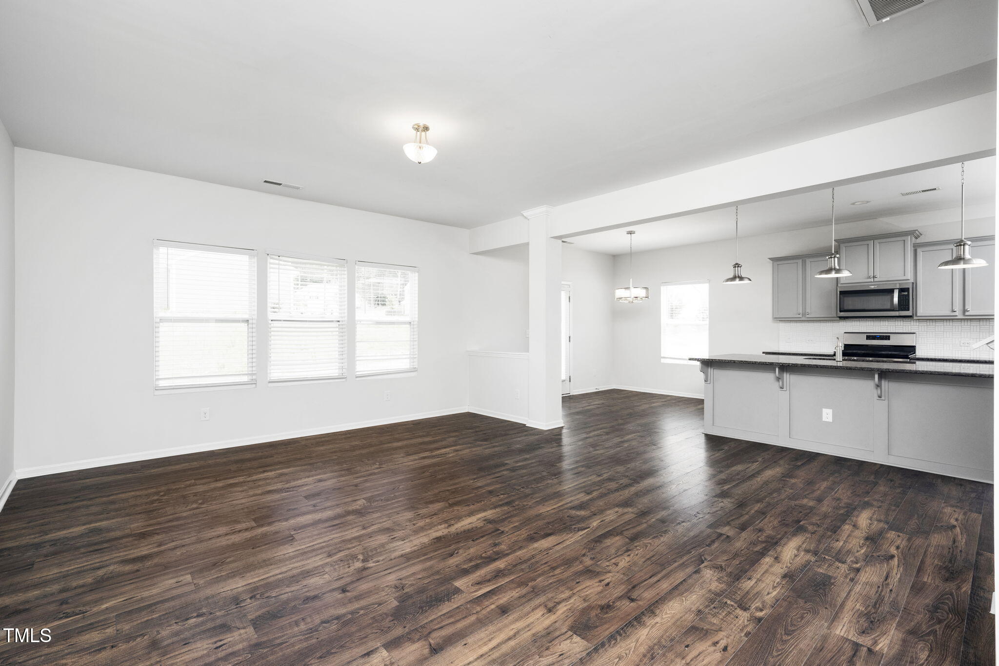 5502 Ripplebrook Drive Durham, NC 27712 - Photo 13 of 50 a view of kitchen with kitchen island granite countertop a stove top oven a sink and white cabinets with wooden floor