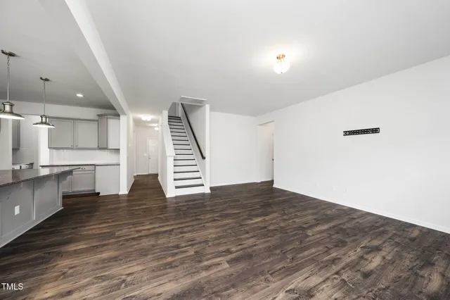 a view of kitchen with kitchen island granite countertop a stove top oven a sink and white cabinets with wooden floor