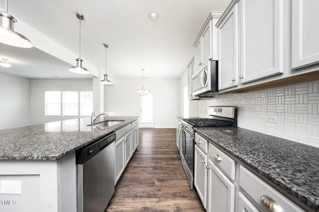 a kitchen with stainless steel appliances kitchen island granite countertop a stove and a sink