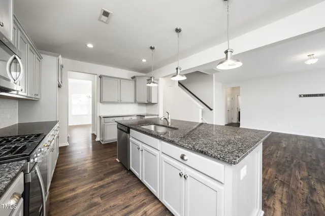 a kitchen with stainless steel appliances granite countertop a sink a stove and a wooden floors