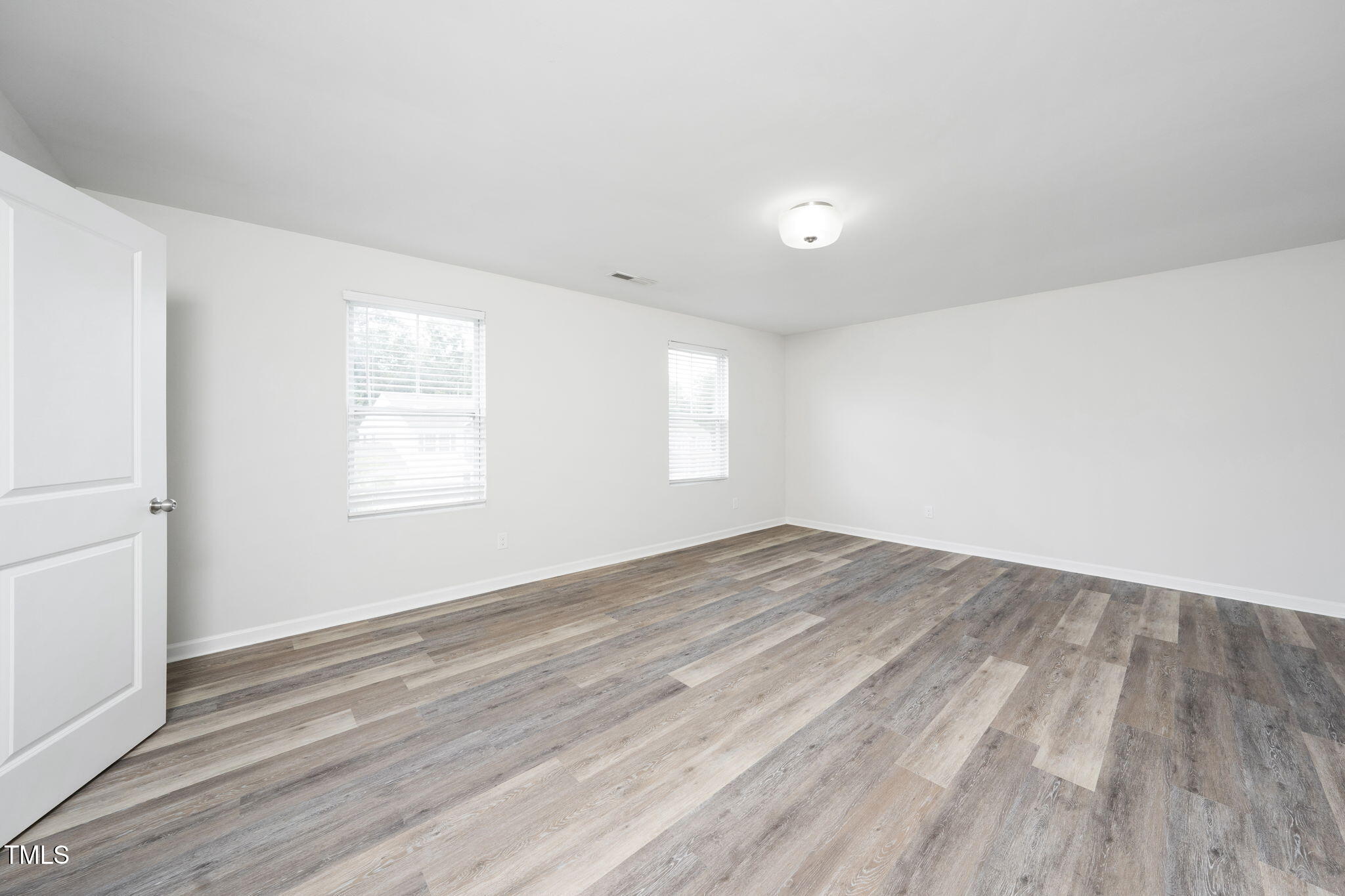 5502 Ripplebrook Drive Durham, NC 27712 - Photo 31 of 50 an empty room with wooden floor and windows