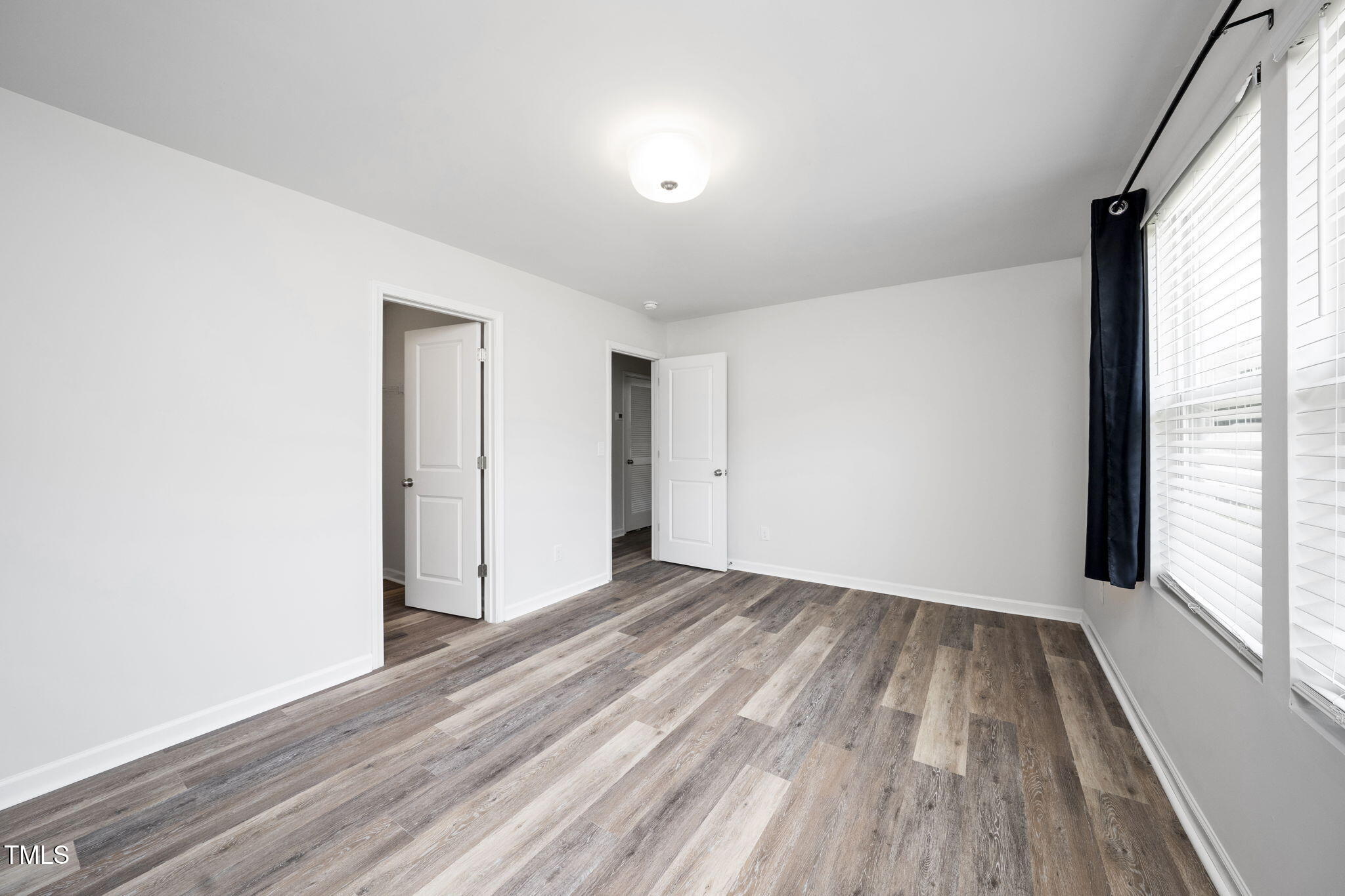 5502 Ripplebrook Drive Durham, NC 27712 - Photo 36 of 50 a view of an empty room with wooden floor and a window