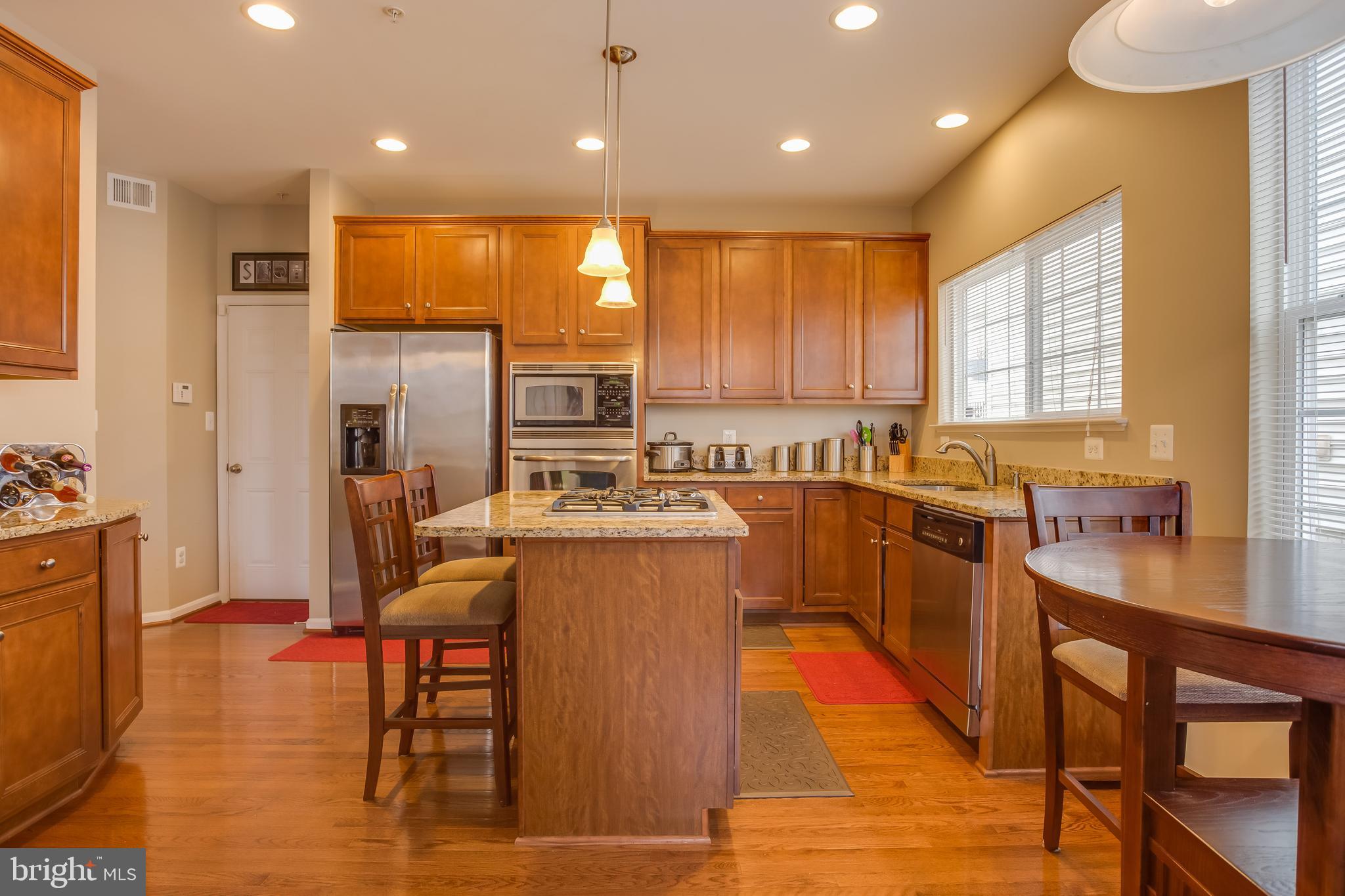 3437 Eagle Ridge Drive Woodbridge, VA 22191 - Photo 12 of 40 a kitchen with stainless steel appliances granite countertop a stove top oven a sink dishwasher and a refrigerator with wooden floor