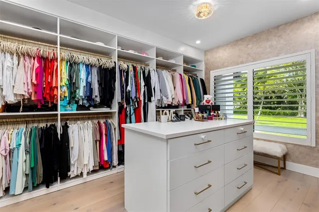 a view of walk in closet with clothes and shoes