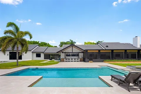 a view of a swimming pool with lawn chairs and a big yard