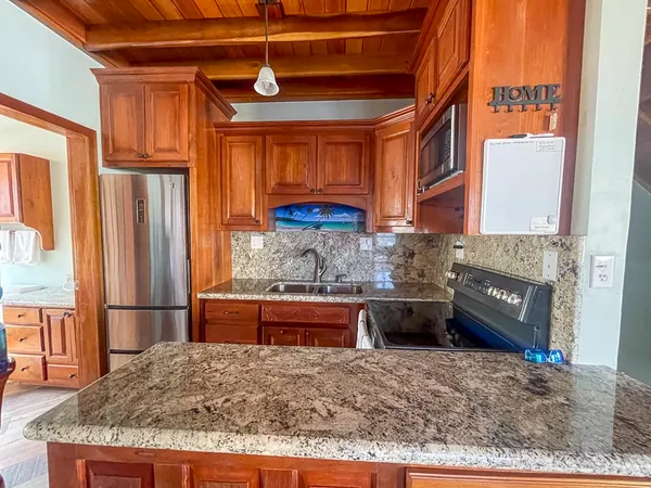 a kitchen with granite countertop a refrigerator and a stove top oven