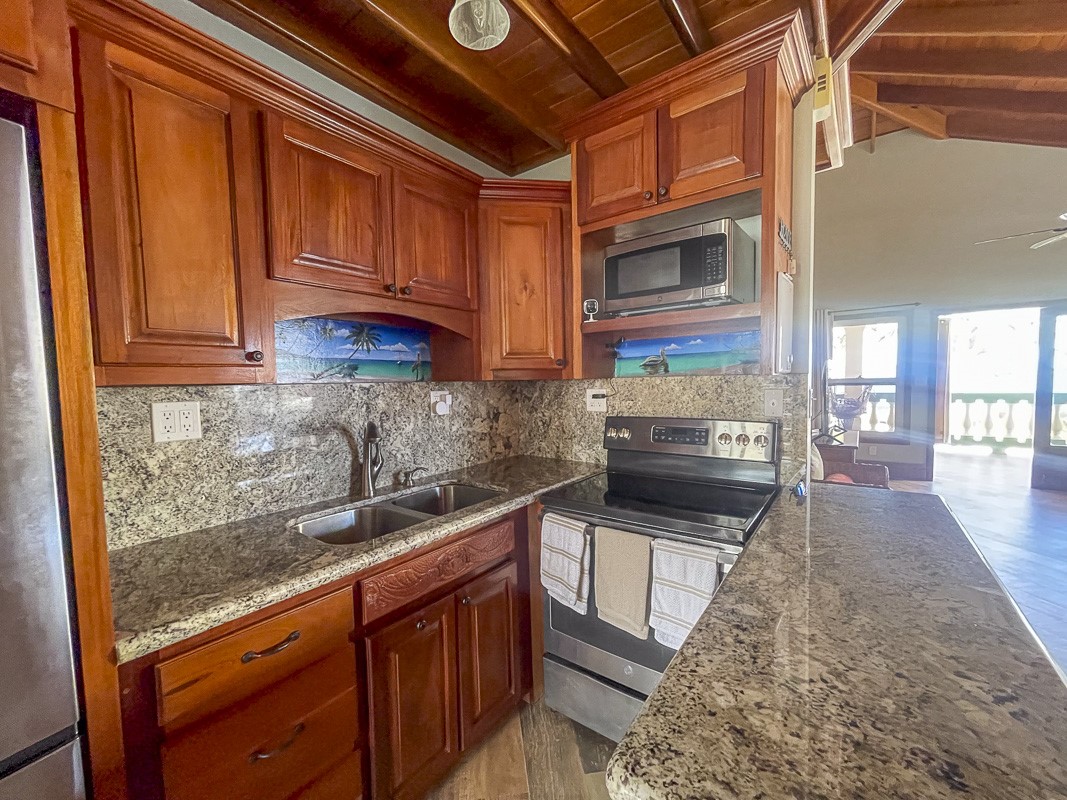 0 Belizean Shores, Unit 11B Robstown, TX 78380 - Photo 10 of 32 a kitchen with granite countertop stainless steel appliances and wooden cabinets