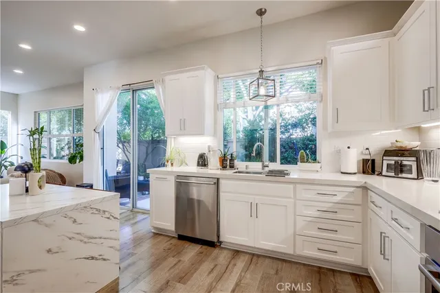 a kitchen with stainless steel appliances granite countertop a refrigerator oven a sink dishwasher and white cabinets with wooden floor