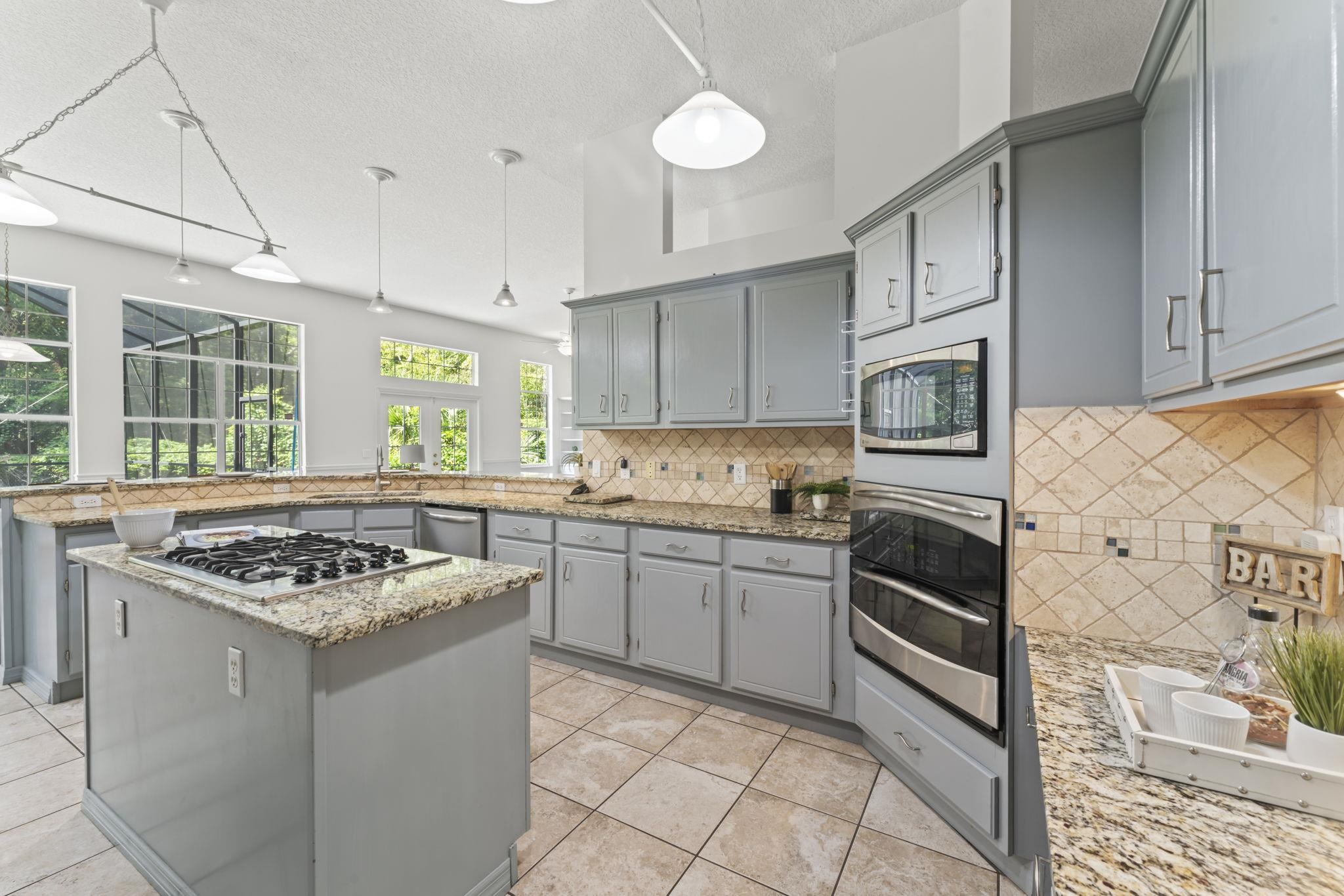 795 Kings Estate Road St. Augustine, FL 32086 - Photo 15 of 90 a kitchen with stainless steel appliances granite countertop a stove a sink dishwasher and white cabinets with wooden floor