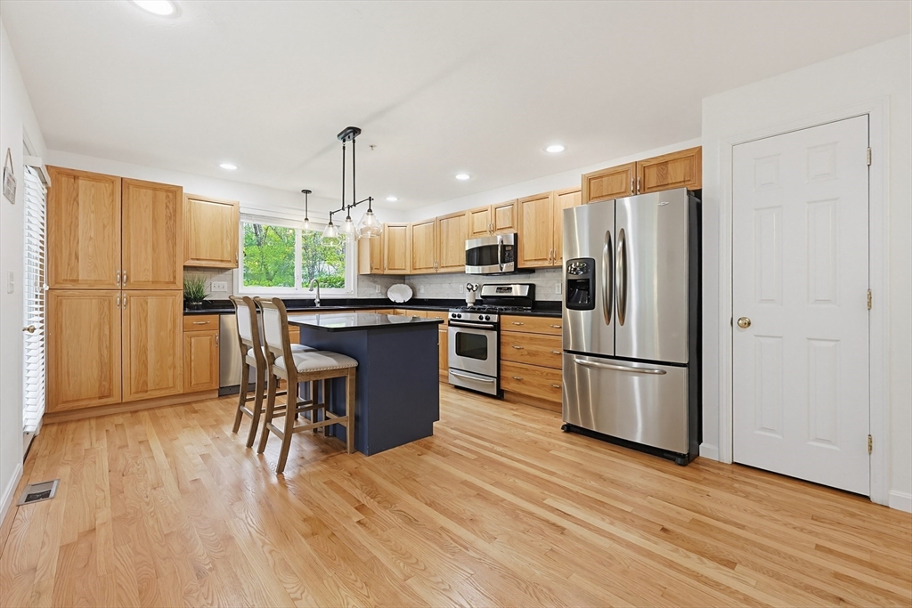 3002 Maple Brook Road, Unit 3002 Bellingham, MA 02019 - Photo 13 of 42 a kitchen with stainless steel appliances a refrigerator a stove a sink dishwasher with a dining table and chairs
