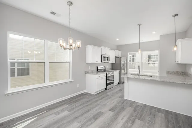 a large white kitchen with lots of counter space wooden floor and appliances