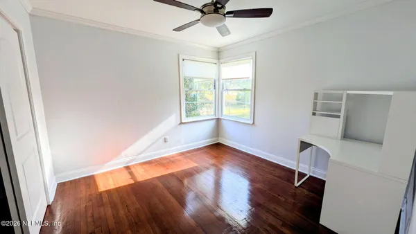 a view of an empty room with a window and wooden floor