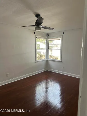 a view of an empty room with wooden floor and a window