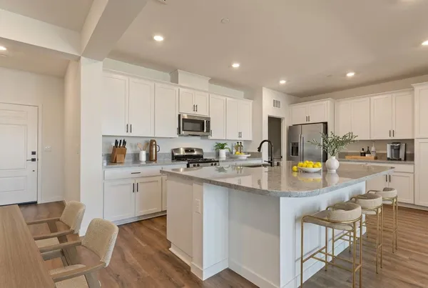 a kitchen with stainless steel appliances a stove a sink a refrigerator a white table and chairs
