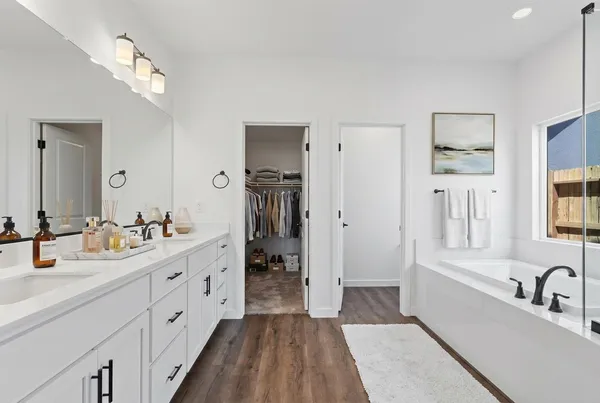 a bathroom with a double vanity sink a mirror a bathtub and shower