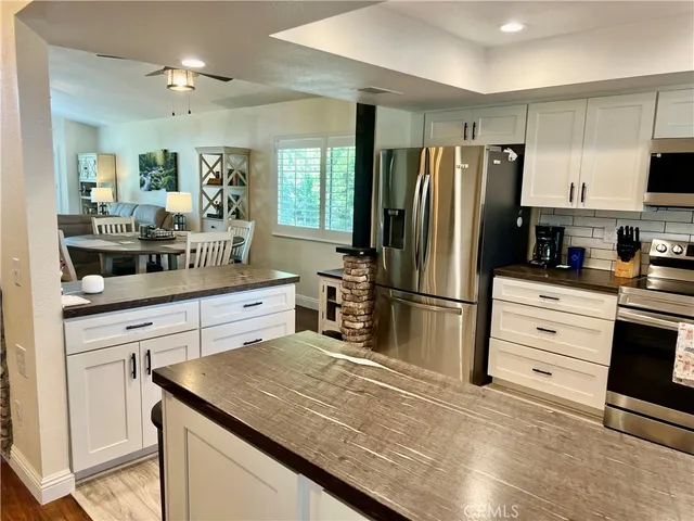 a kitchen with stainless steel appliances a dining table chairs and refrigerator
