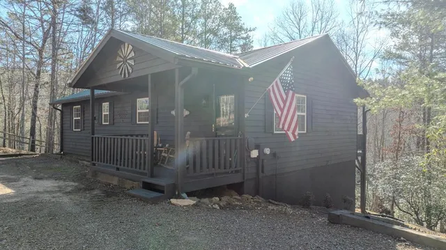 a view of a wooden house with a small yard and large tree