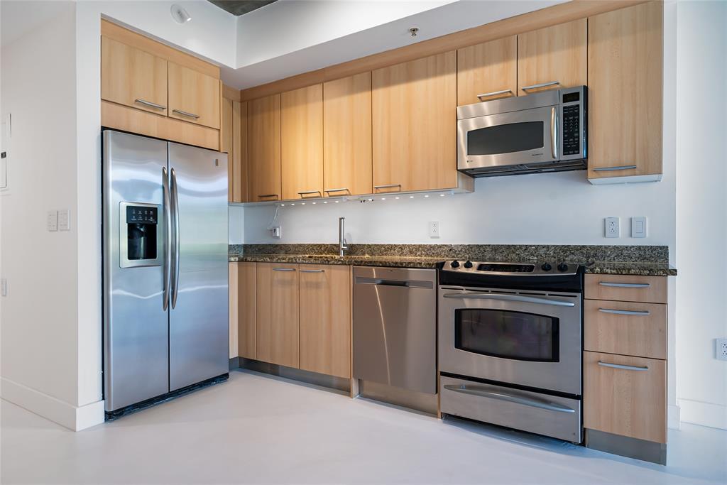 2001 Meridian Avenue, Unit 318 Miami Beach, FL 33139 - Photo 15 of 37 a kitchen with stainless steel appliances granite countertop white cabinets a microwave a sink and a refrigerator